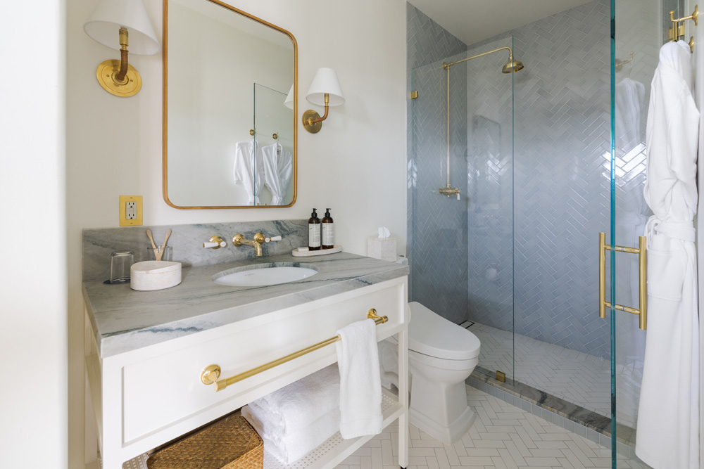 bathroom with marble, brass fixtures and blue tile shower